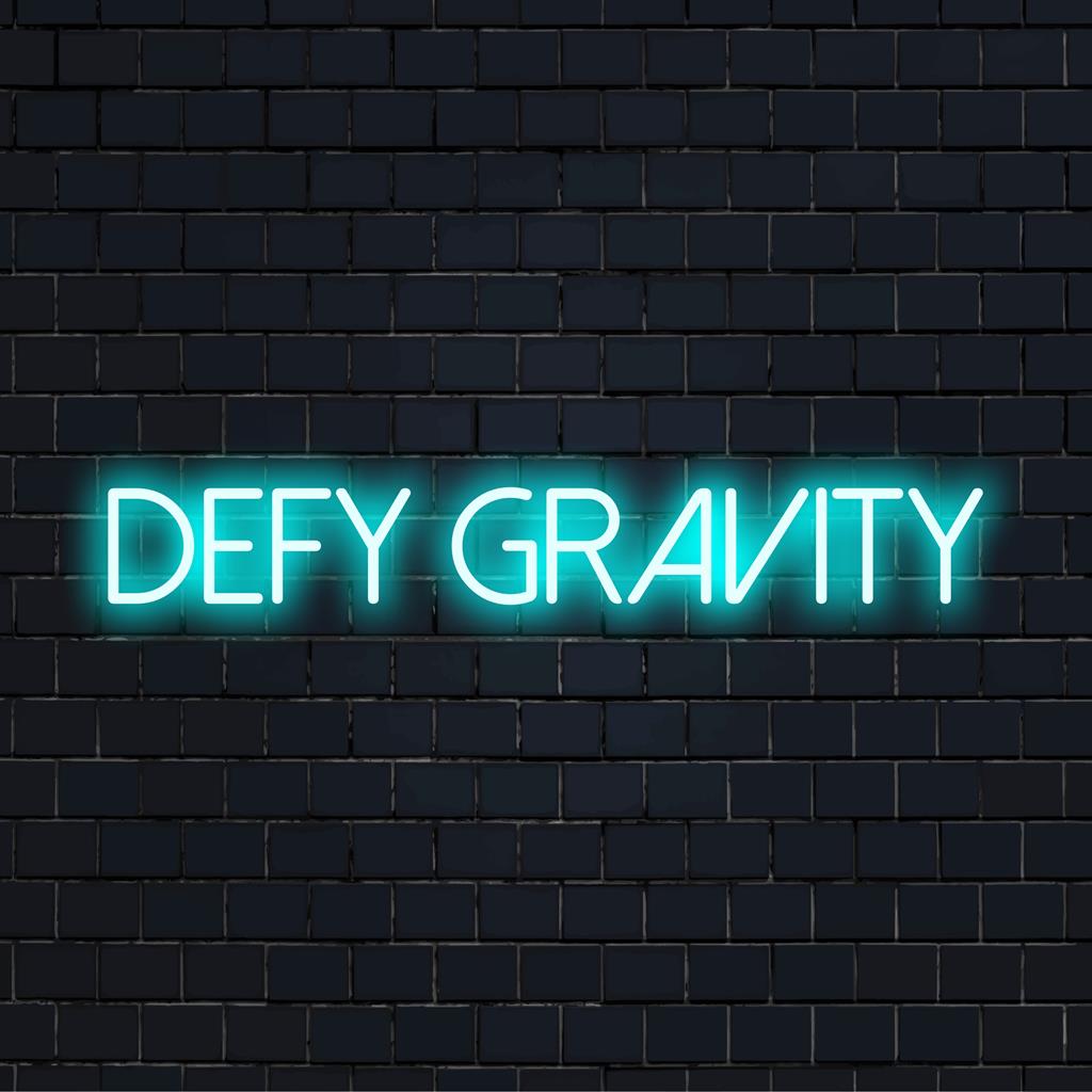 LED neonskylt som läser Defy Gravity, perfekt för inspirerande inredning, med en blandning av konstnärliga bokstäver och självlysande ljus.