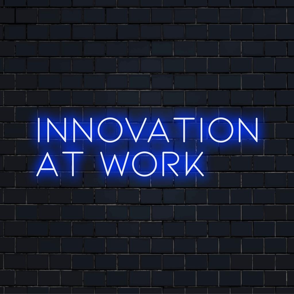 Anpassad LED-neonskylt med frasen Innovation At Work, glödande i livfulla färger, perfekt för modern kontorsinredning.