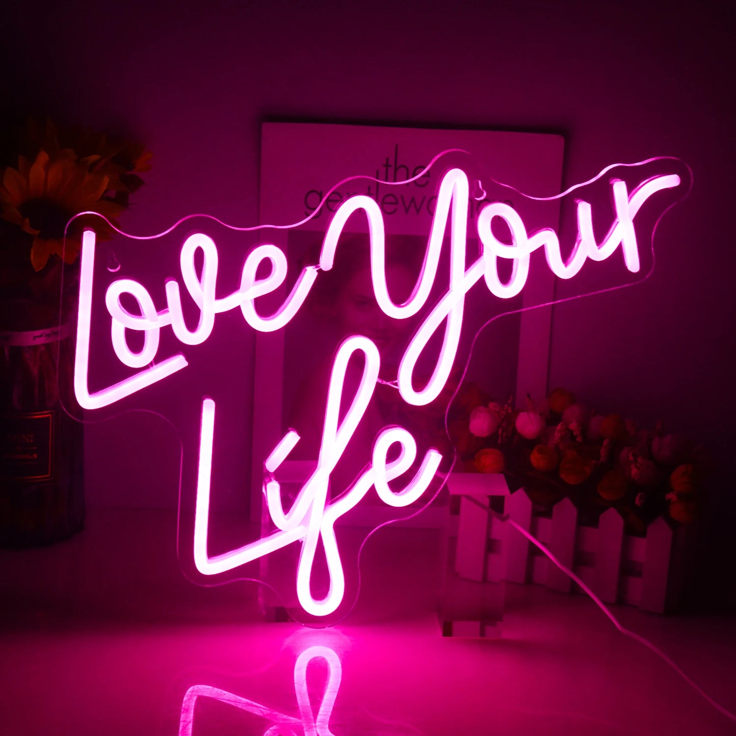 En starkt upplyst LED-neonskylt som visar orden "Love Your Life" i ett elegant, kursivt manus.