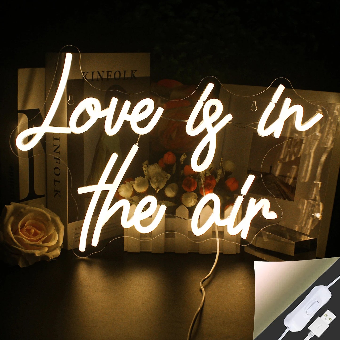 Bilden har en levande och elegant LED-neonskylt som läser "Love is in the Air" i elegant kursivt manus.