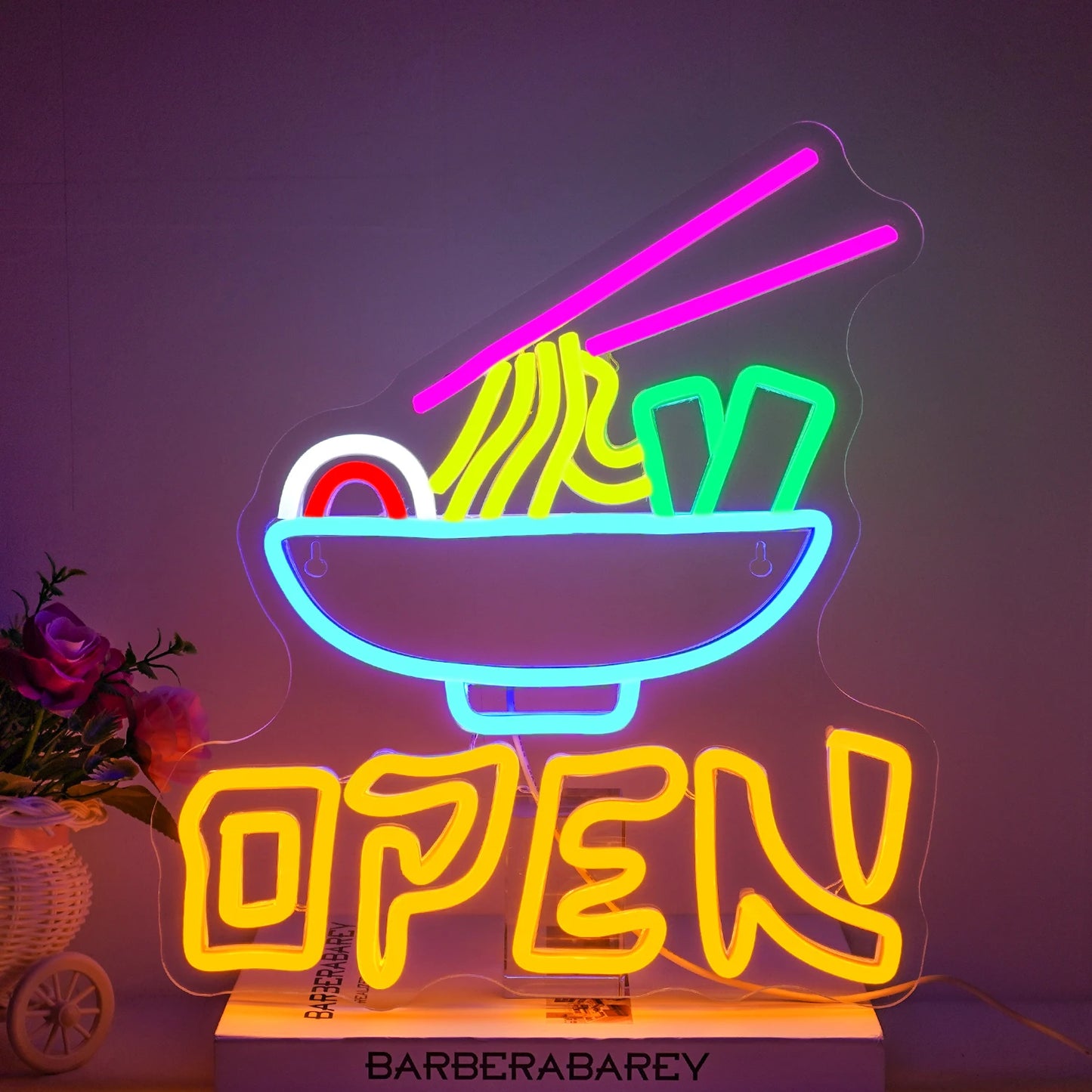 Bilden har en levande LED-neonskylt som läser "Open Ramen" i visuellt slående, glödande färger.