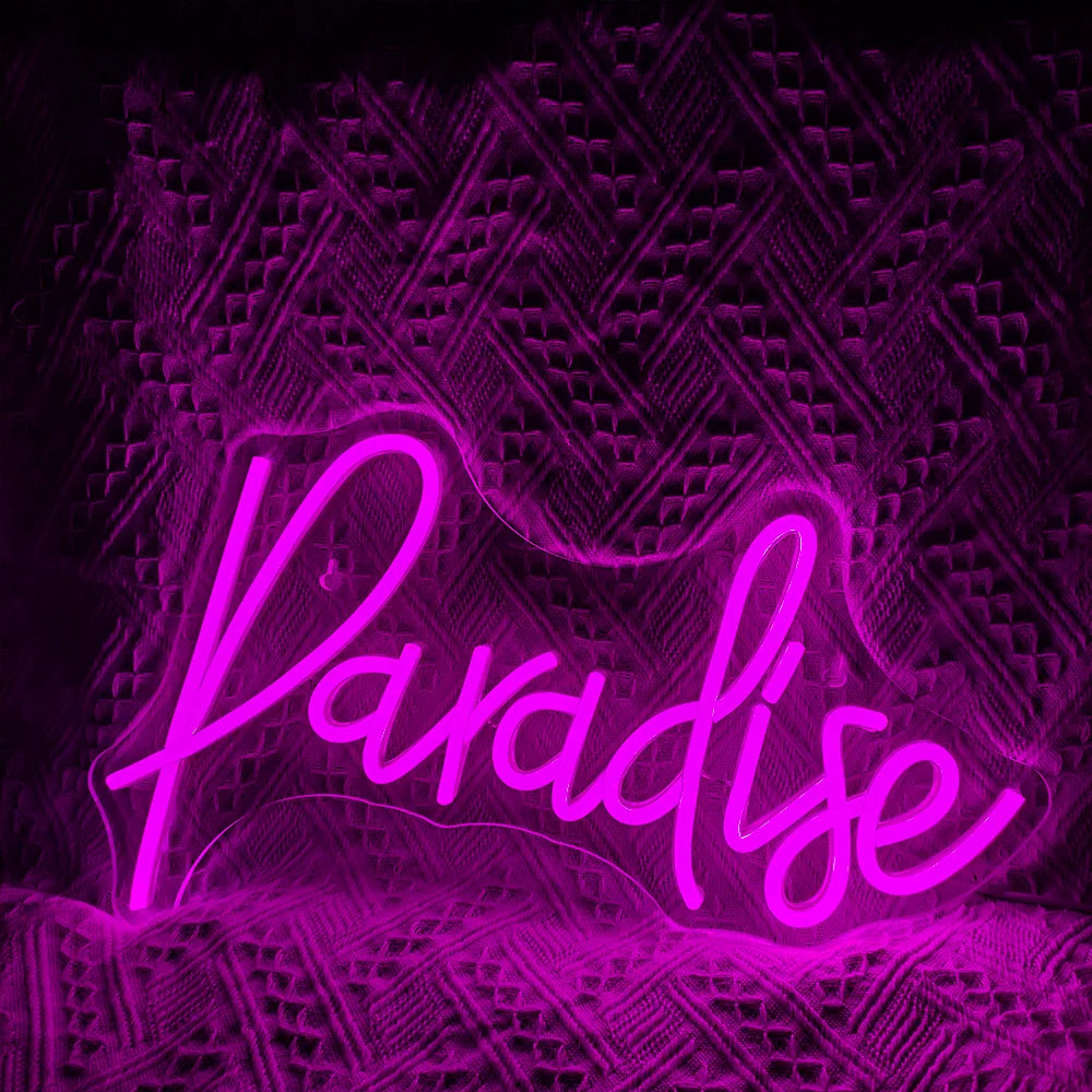 Bilden visar en levande, handgjord LED-neonskylt som stavar ordet "Paradise" i ett lekfullt kursivt teckensnitt.
