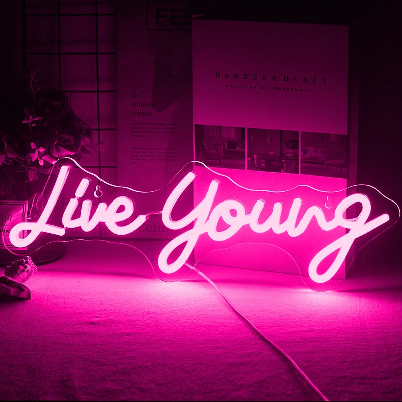 Bilden visar en levande handgjord LED-neonskylt med frasen "Live Young" i ett livligt, kursivt manus.