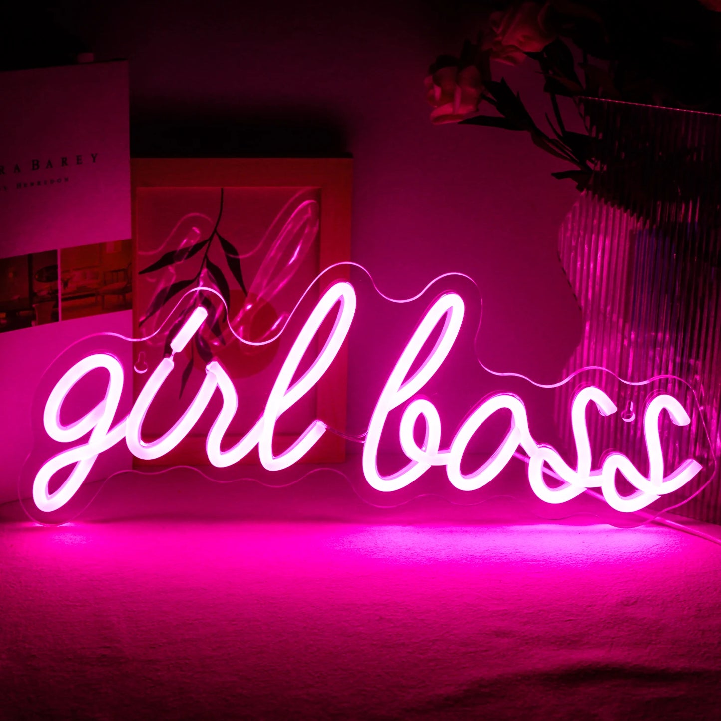 Bilden visar en levande, handgjord LED-neonskylt som stavar ut "Girl Boss" i ett elegant, kursivt teckensnitt.