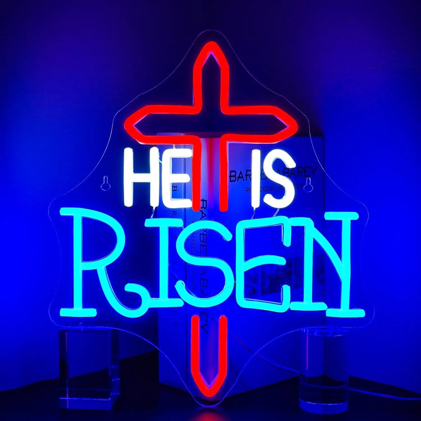 Bilden har en levande "He Is Risen" LED-neonskylt som lyser i djärva, varma nyanser.