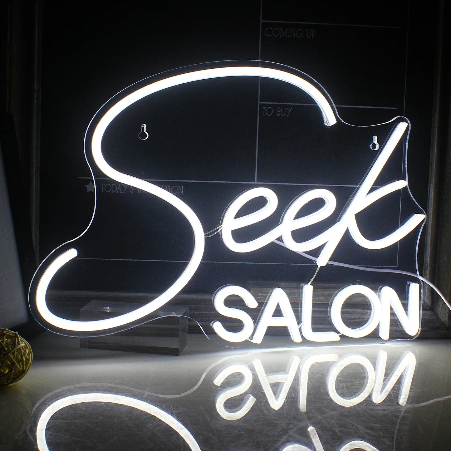 Bilden har en levande LED-neonskylt som visar ordet "SALON" med stiliserade versaler.