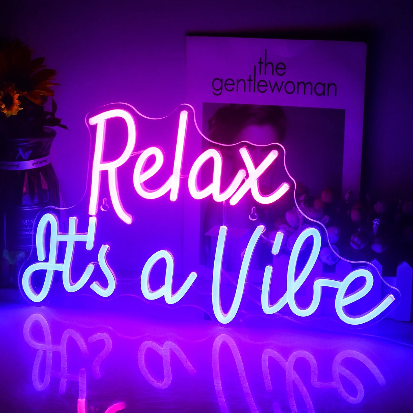 Bilden visar en levande LED-neonskylt som visar frasen "Relax It's a Vibe" i ett elegant, kursivt teckensnitt.