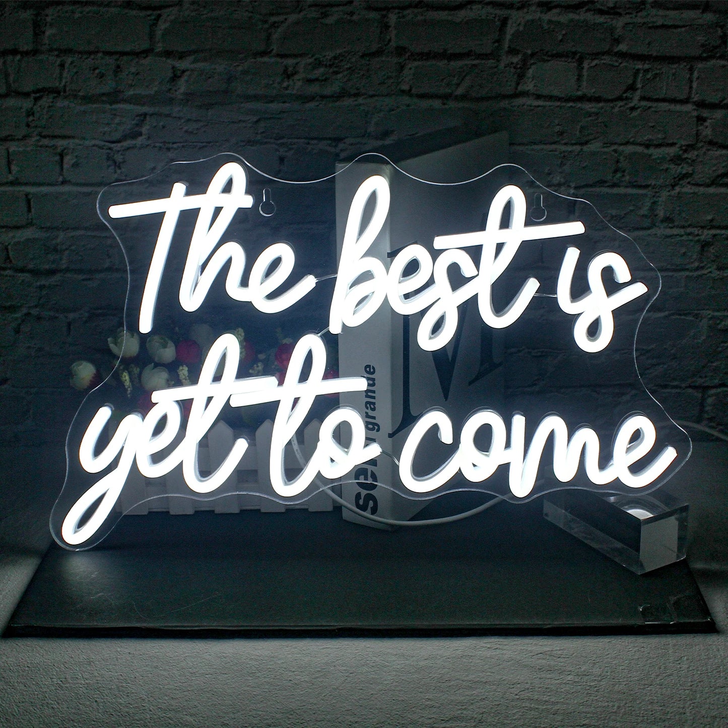 Bilden visar en levande, handgjord LED-neonskylt som läser "The Best is Yet to Come" i ett elegant, kursivt teckensnitt.