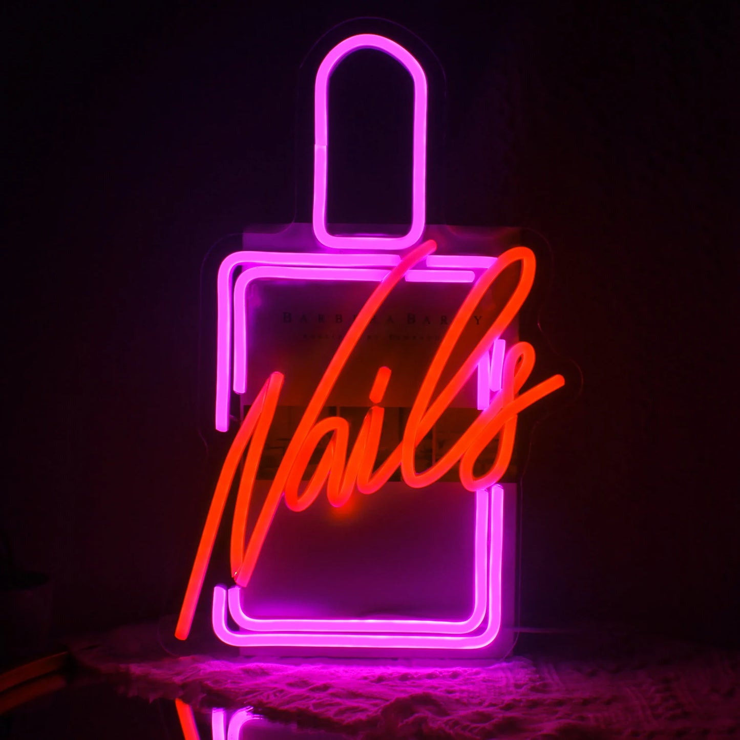 Bilden har en levande LED-neonskylt som stavar ut ordet "Nails" i ett stilfullt kursivt teckensnitt.