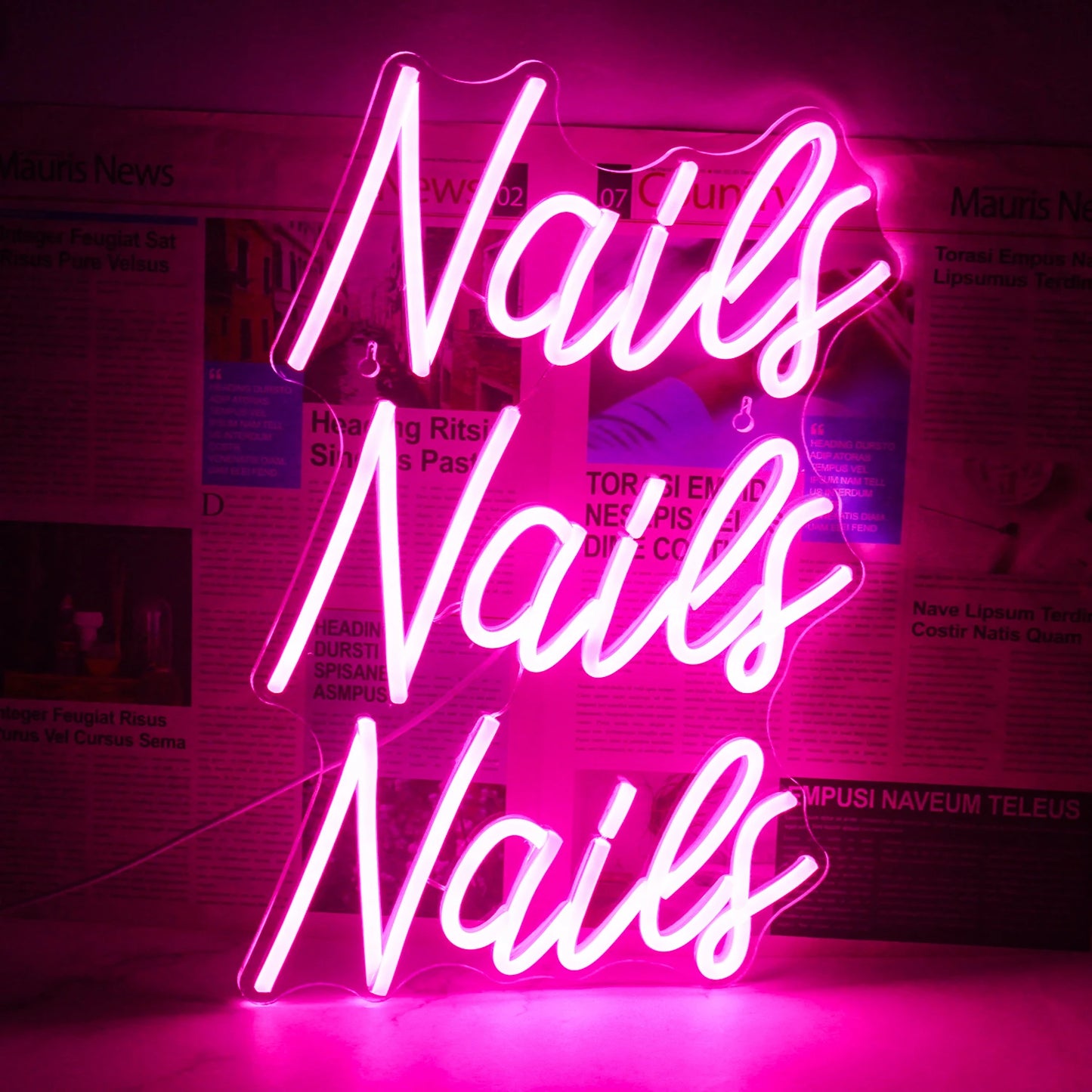 Bilden har en levande och iögonfallande LED-neonskylt som stavar ut ordet "Nails" i ett stilfullt, kursivt teckensnitt.