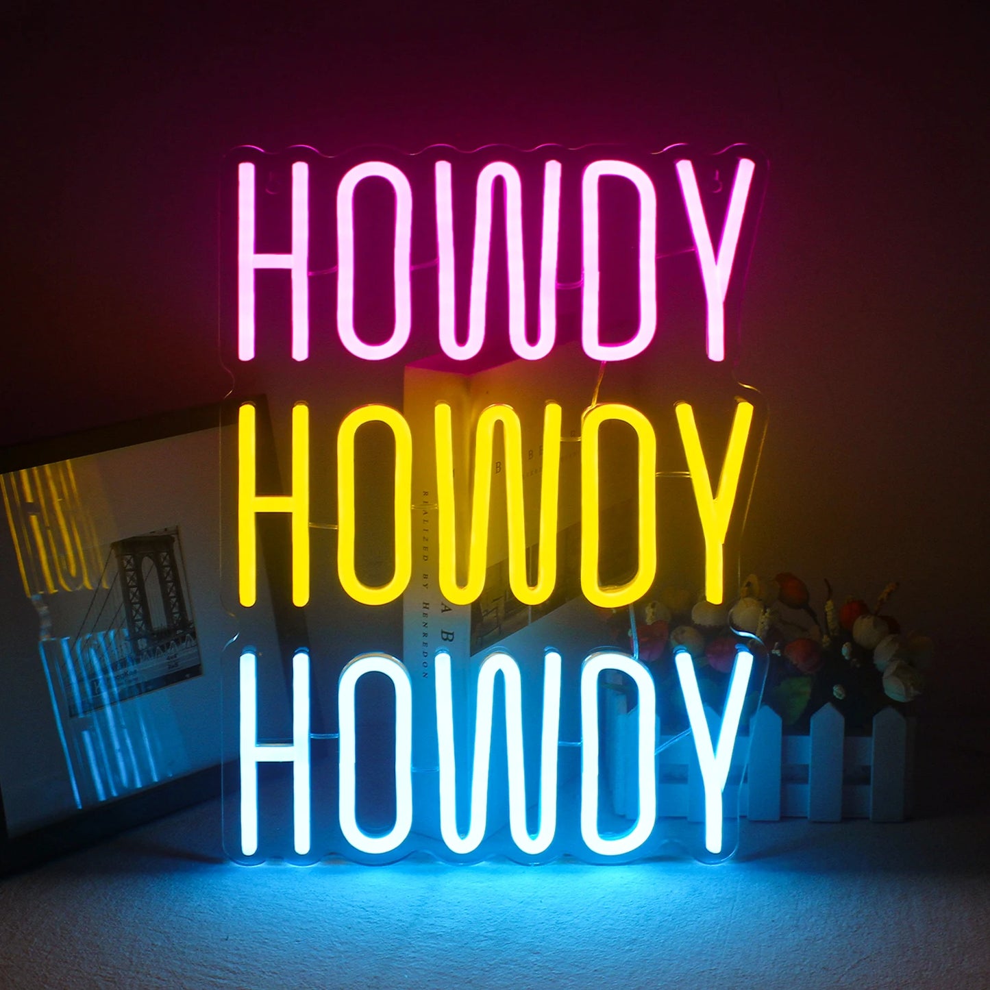 En levande, handgjord LED-neonskylt som visar ordet "Howdy" i ett lekfullt, kursivt teckensnitt.