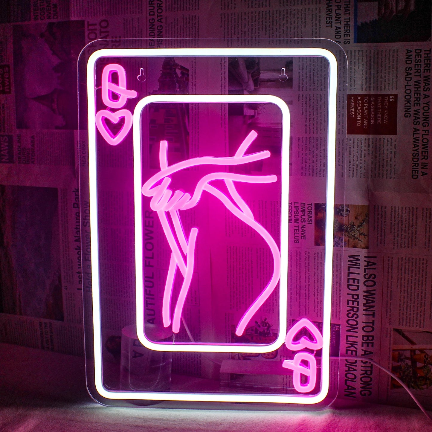 Bilden har en LED-neonskylt som visar en stiliserad representation av en kvinna som består av spelkortselement.