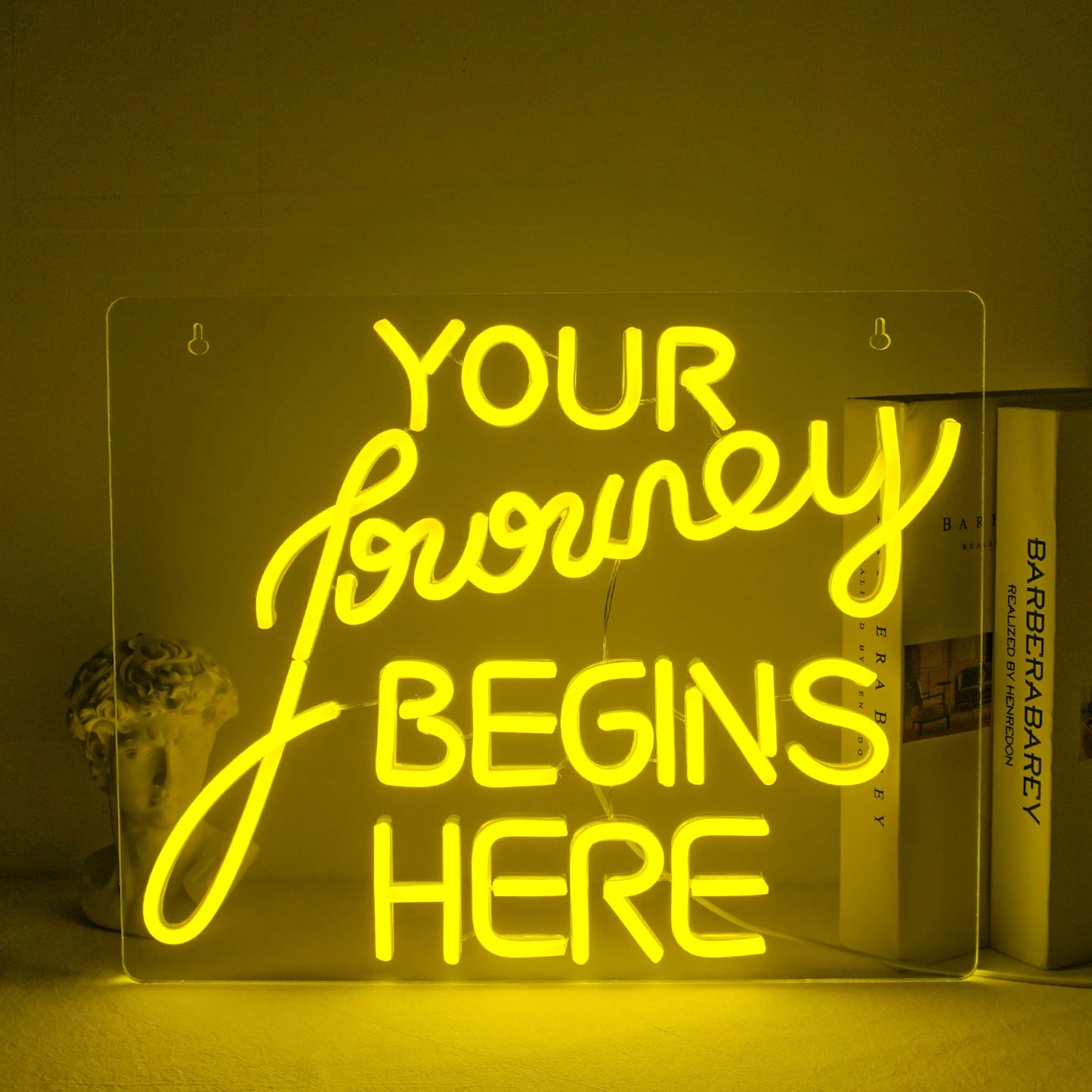 "En handgjord LED-neonskylt som visar orden "Journey Begin" i ett flödande skrifttypsnitt.