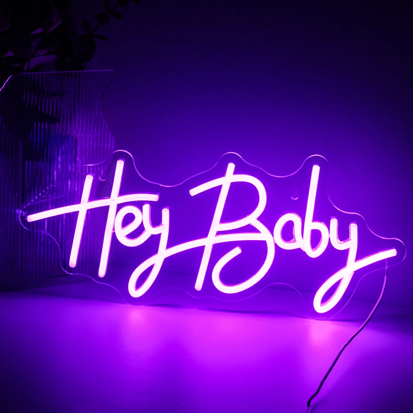 Bilden visar en levande, handgjord LED-neonskylt som läser "Hey Baby" i ett lekfullt kursivt teckensnitt.