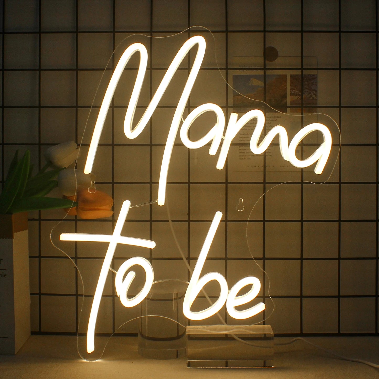 Bilden har en levande och elegant LED-neonskylt som visar frasen "Mama to Be" med eleganta, kursiva bokstäver.