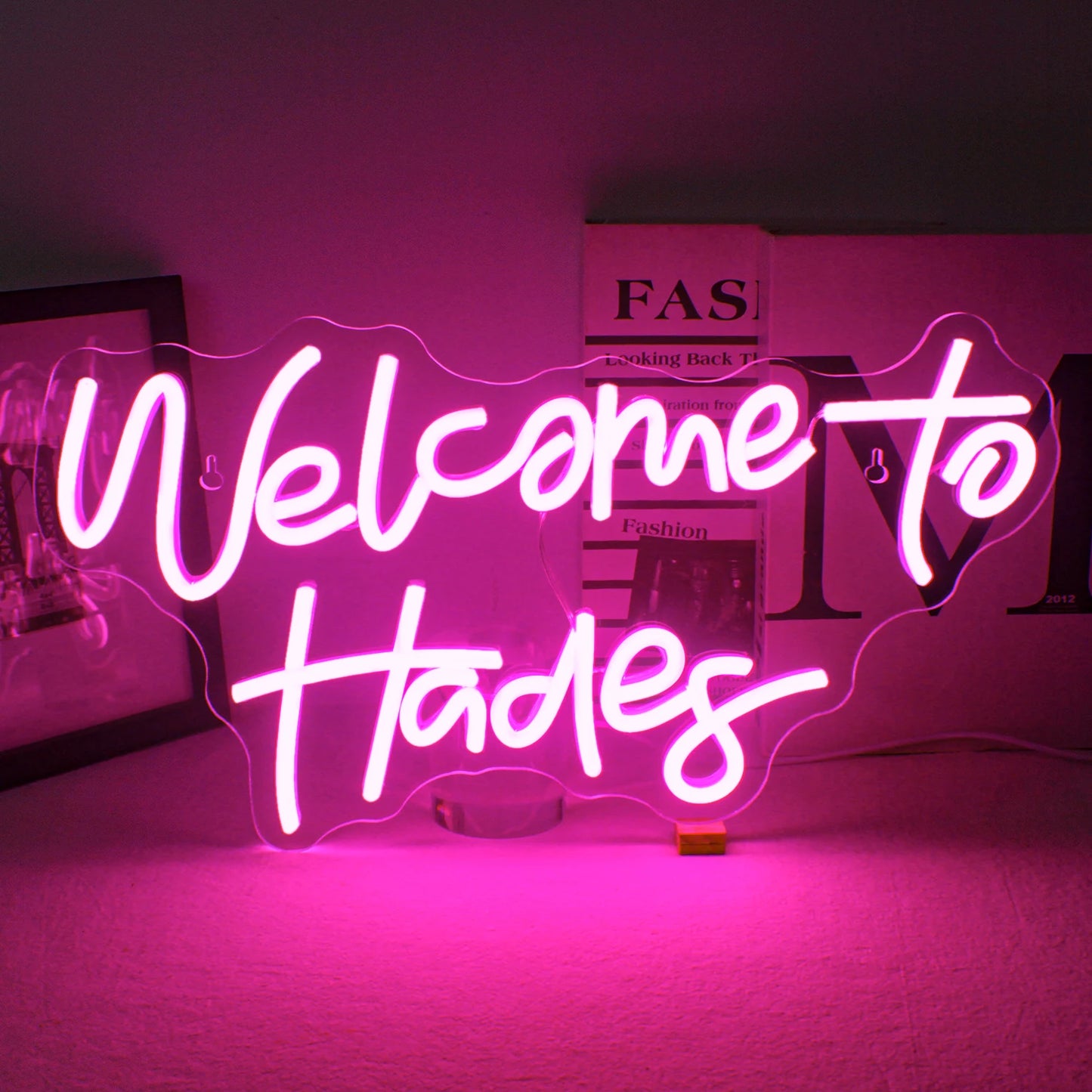 En LED-neonskylt som stavar orden "Welcome to Hades" i ljusa, glödande neonljus.