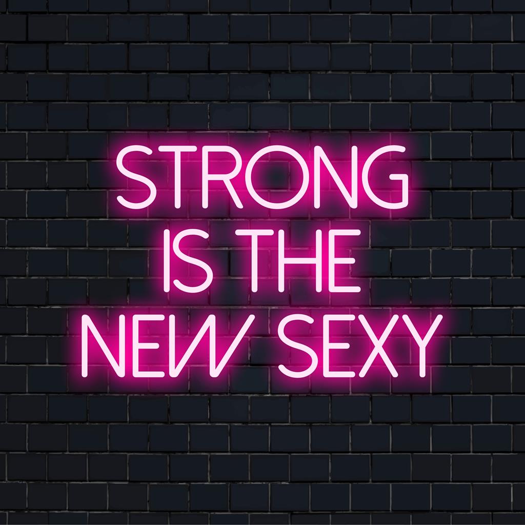 LED neonskylt med frasen Strong Is The New Sexy; levande, motiverande väggkonst som lyser upp i glödande färger.