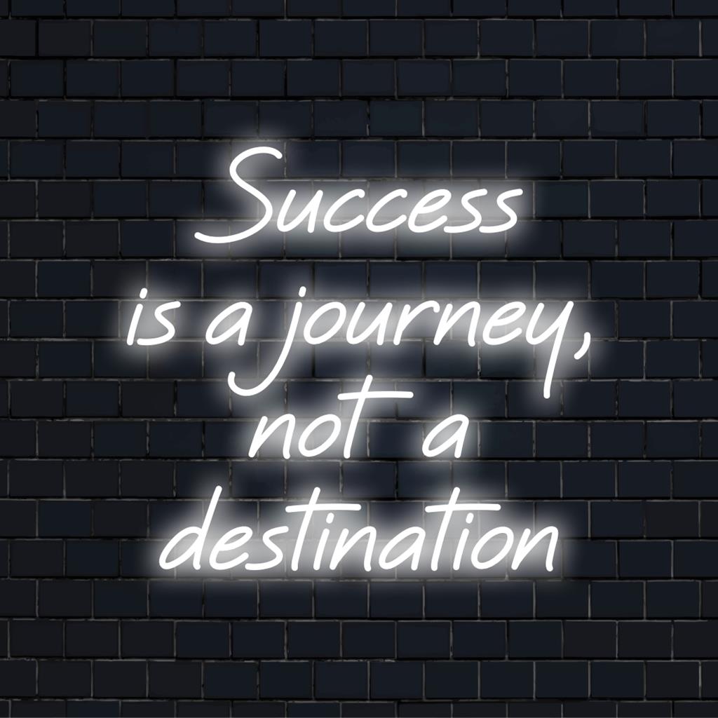 Anpassad LED-neonskylt som lyser upp frasen Success Is A Journey, Not A Destination i ljus konstnärlig neontypografi.