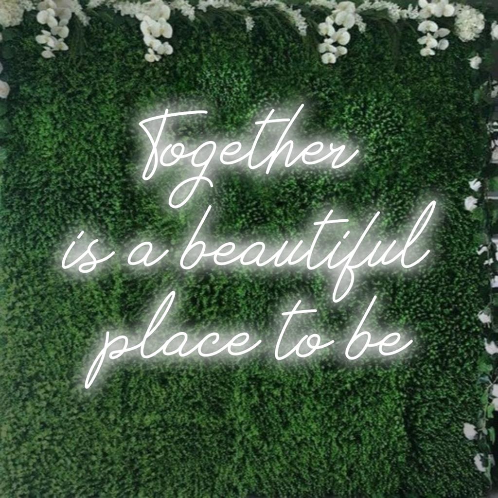 En skräddarsydd LED-neonskylt med citatet Together Is A Beautiful Place To Be glödande i livfulla nyanser, perfekt för heminredning.