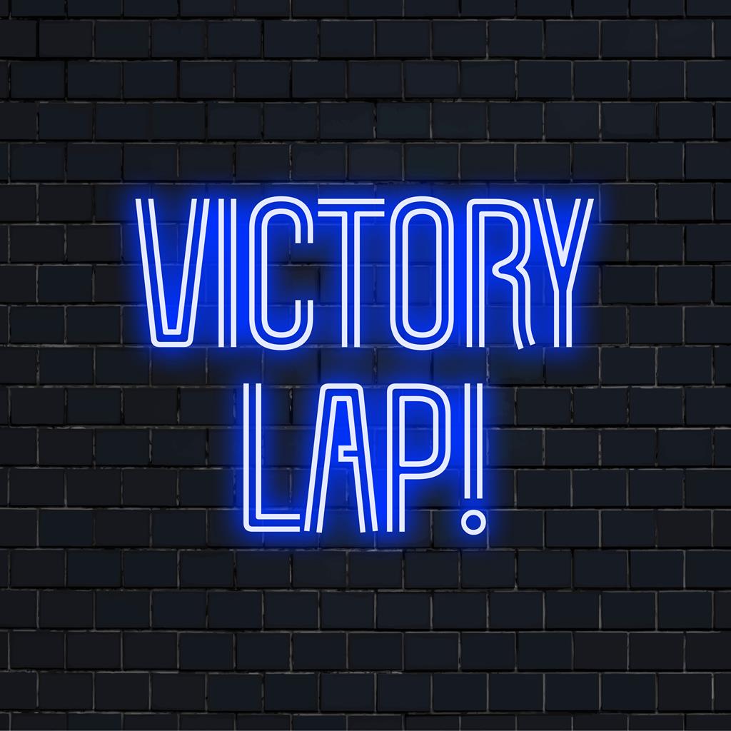 Anpassad neonskylt med frasen Victory Lap! i ljusa färger, lyser upp alla utrymmen, perfekt som personlig neondekor.