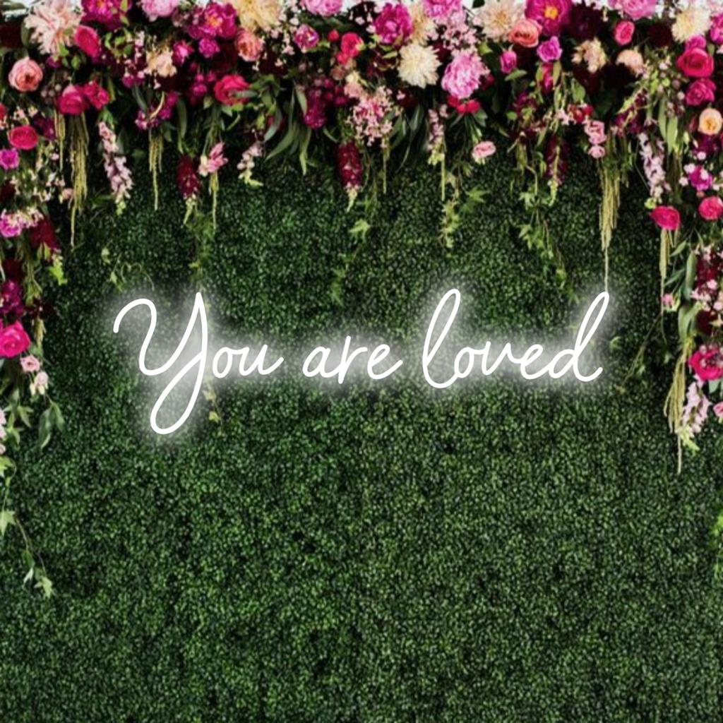 En livlig anpassad LED-neonskylt med meddelandet You Are Loved som lyser upp utrymmen med värme och uppmuntran.
