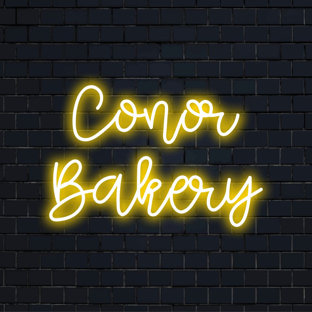 Conor Bakery Custom Name Neon Sign, bright neon glow against black brick wall