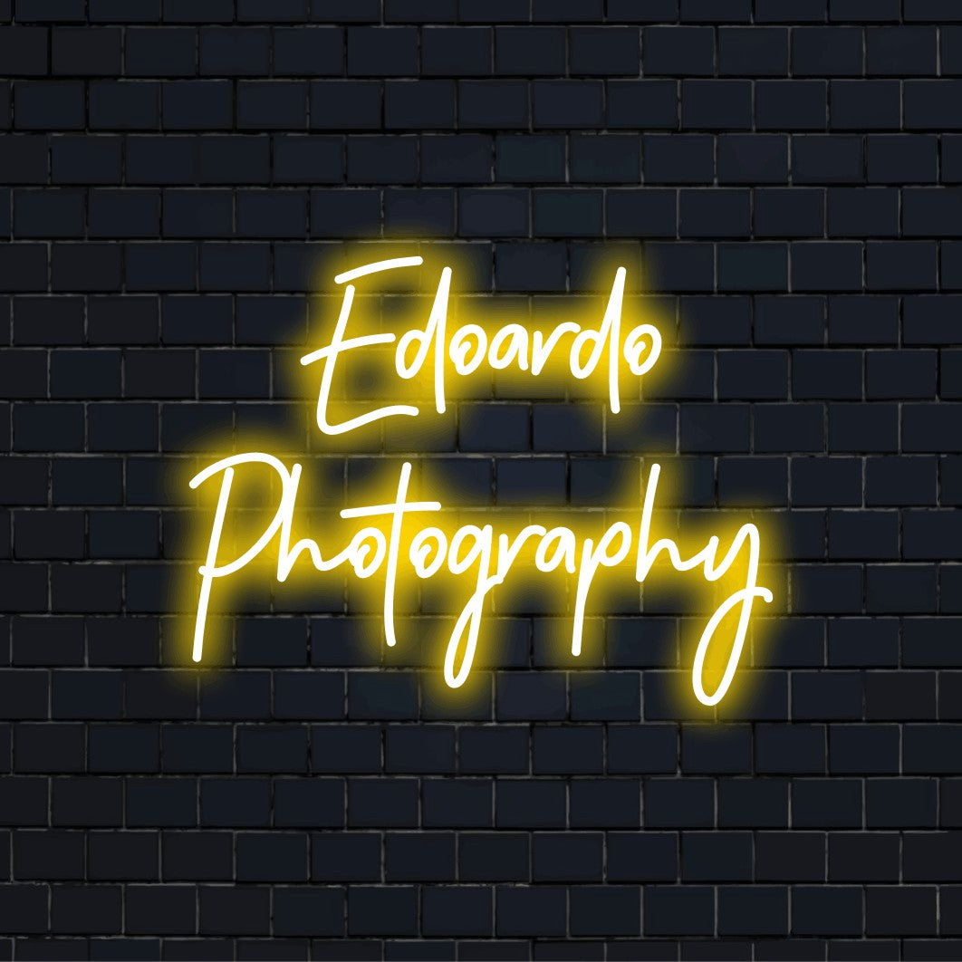 Edoardo Photography Custom Name Neon Sign, glowing neon text against brick backdrop