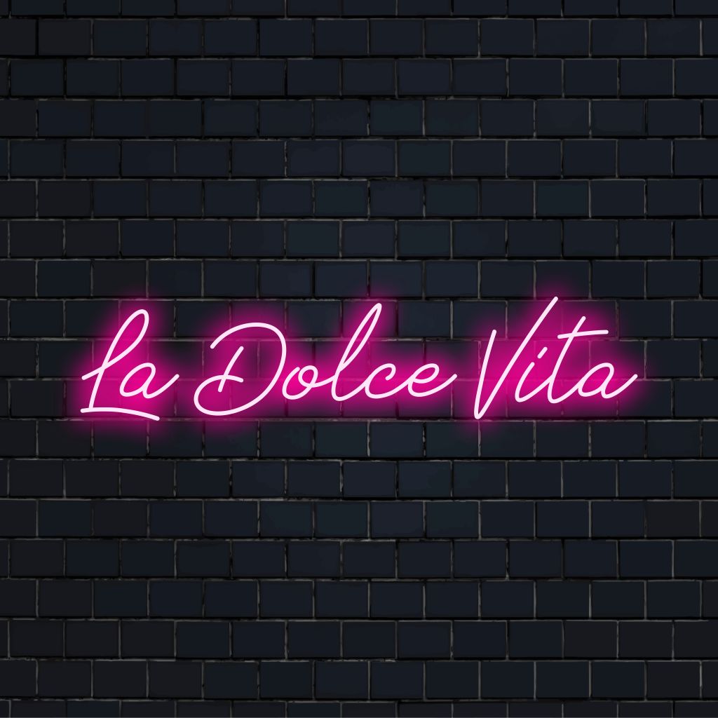 La Dolce Vita Neon Light with glowing lettering against black brick wall
