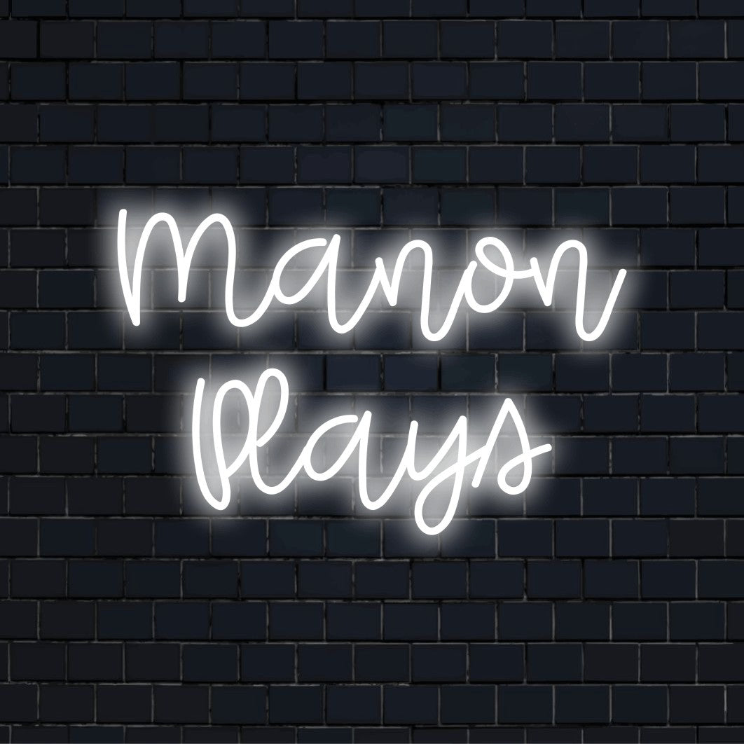Manon Plays Custom Name Neon Sign, bright LED glow on black brick background