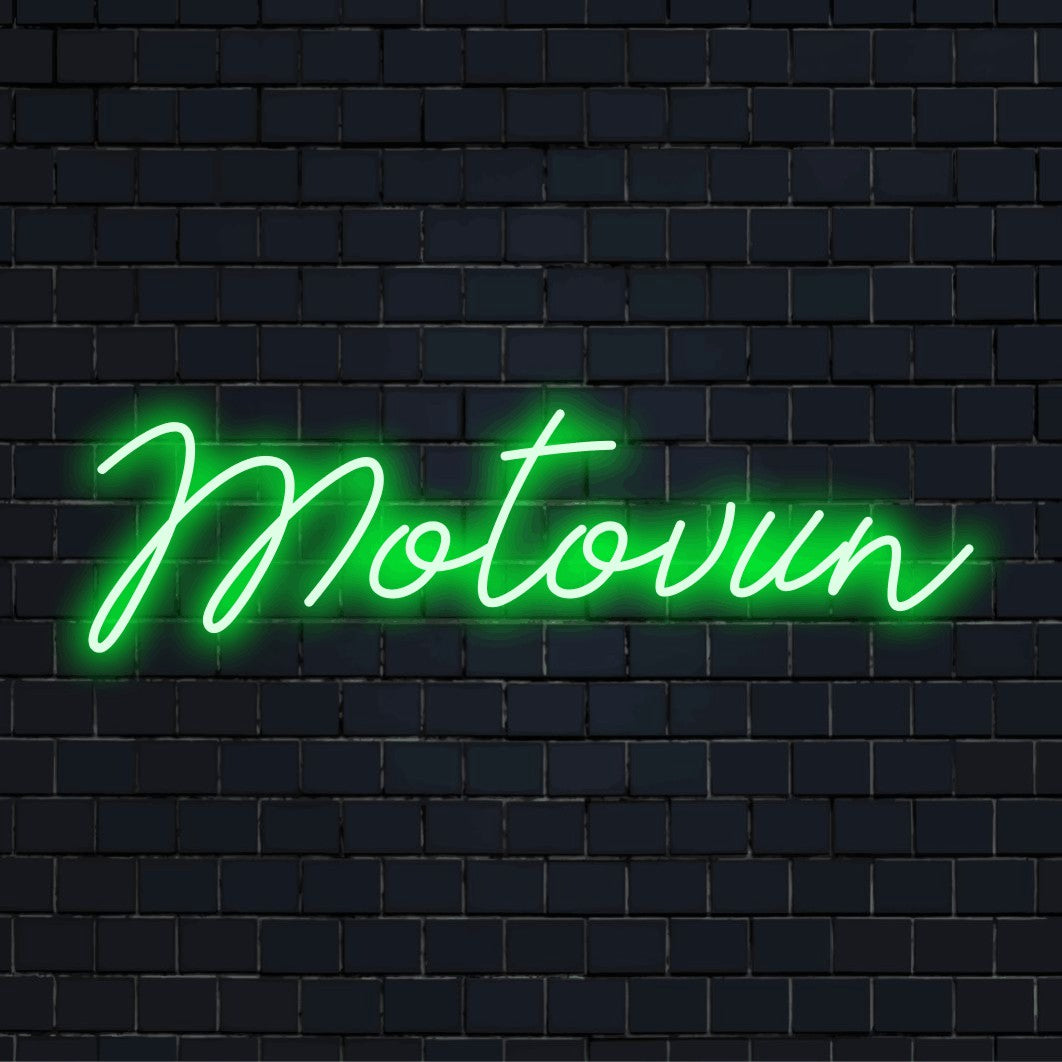 Motovun Neon Light with bright neon lettering against black brick wall