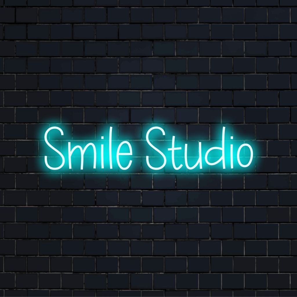 Smile Studio LED Neon Sign, bright neon glow on black brick background
