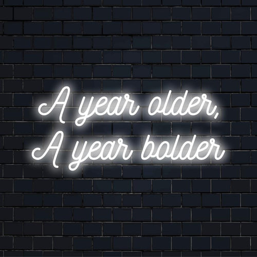 Livlig LED-neonskylt med texten A Year Older, A Year Bolder som slående neonväggkonst och anpassad ljusdekor.