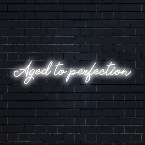 LED-neonskylt som visar Aged To Perfection i stilfullt manus, perfekt för att ge en personlig touch till alla utrymmen.
