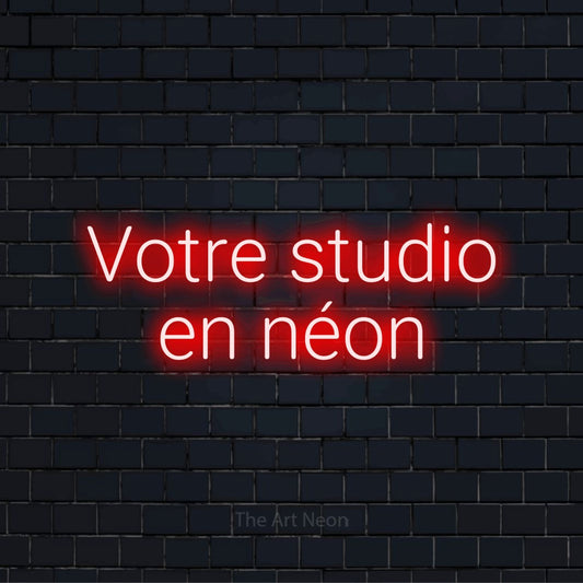 Enseigne néon personnalisée « Votre studio en néon » sur un mur en briques noires
