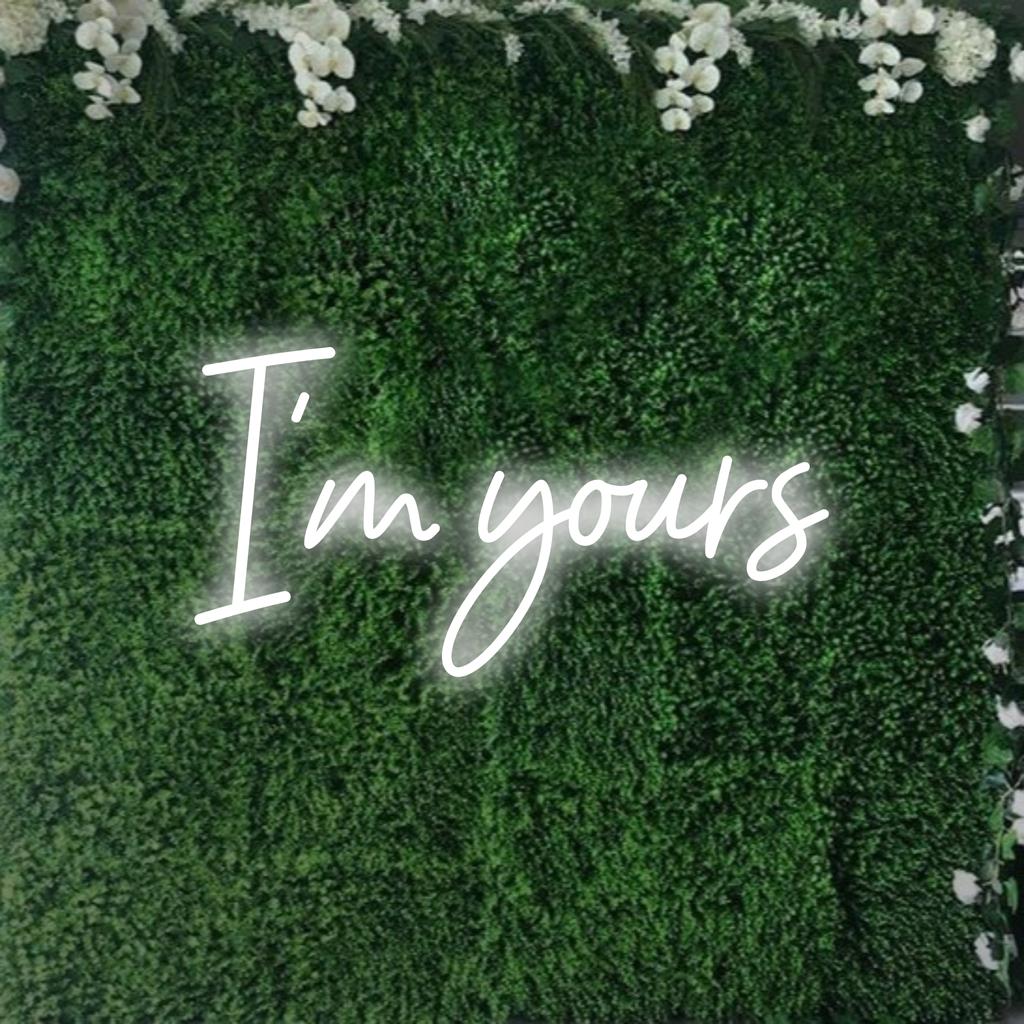 Snygg LED-neonskylt med "I'm Yours" i elegant manus, glödande varmt som anpassningsbar neondekorkonst.