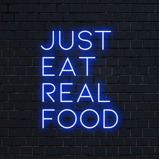 Vibrant neon sign with the message Just Eat Real Food in glowing LED lights; perfect for modern decor and wellness enthusiasts.