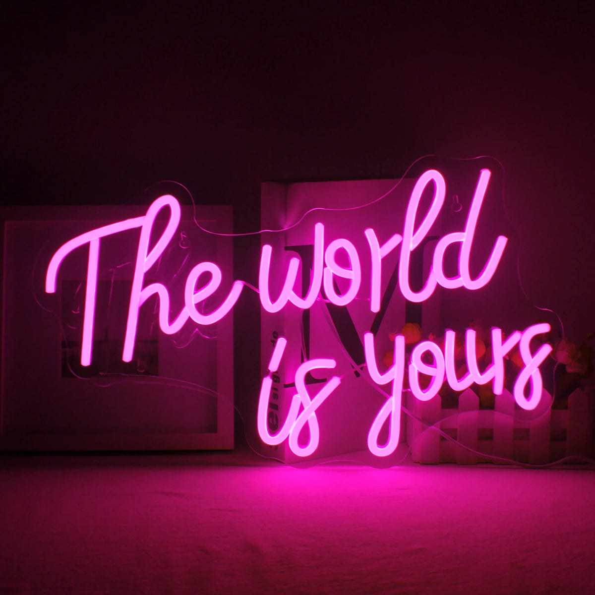 En livlig LED-neonskylt som visar orden "The World Is Yours" i ett elegant, kursivt teckensnitt.