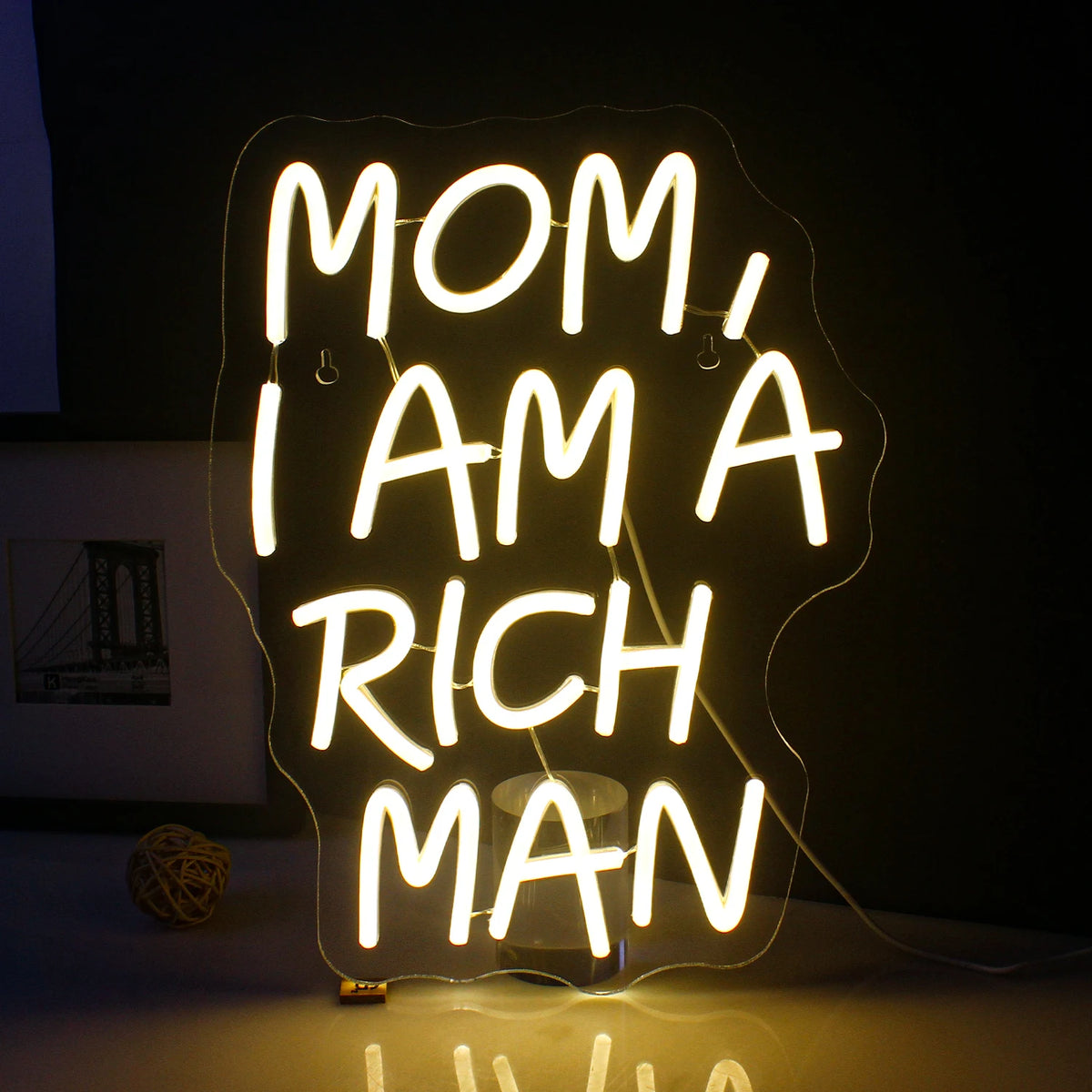 En livlig LED-neonskylt som visar frasen "Mom I Am A Rich Man" med eleganta, kursiva bokstäver.
