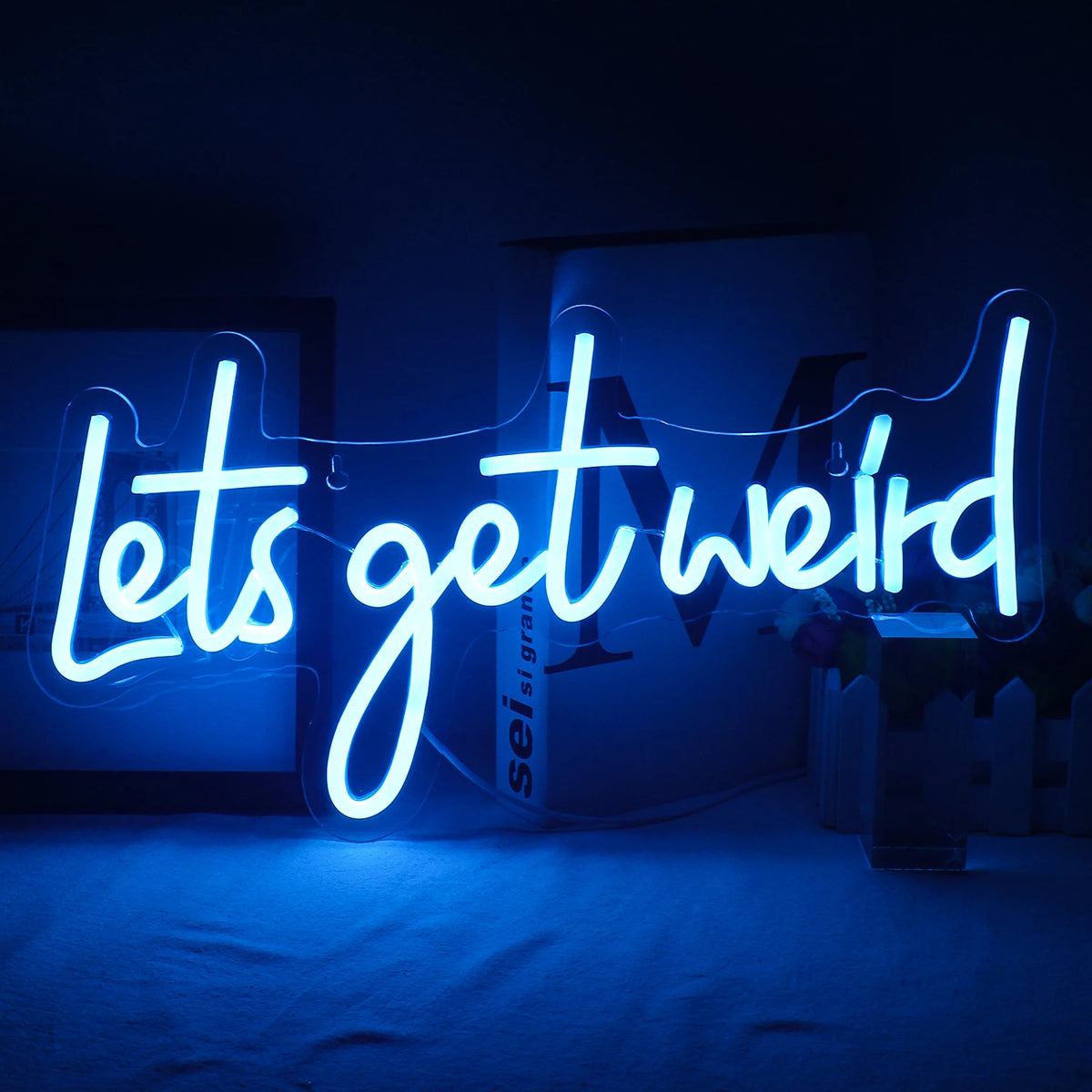 Bilden visar en livlig "Let's Get Weird" LED-neonskylt monterad på en vägg.