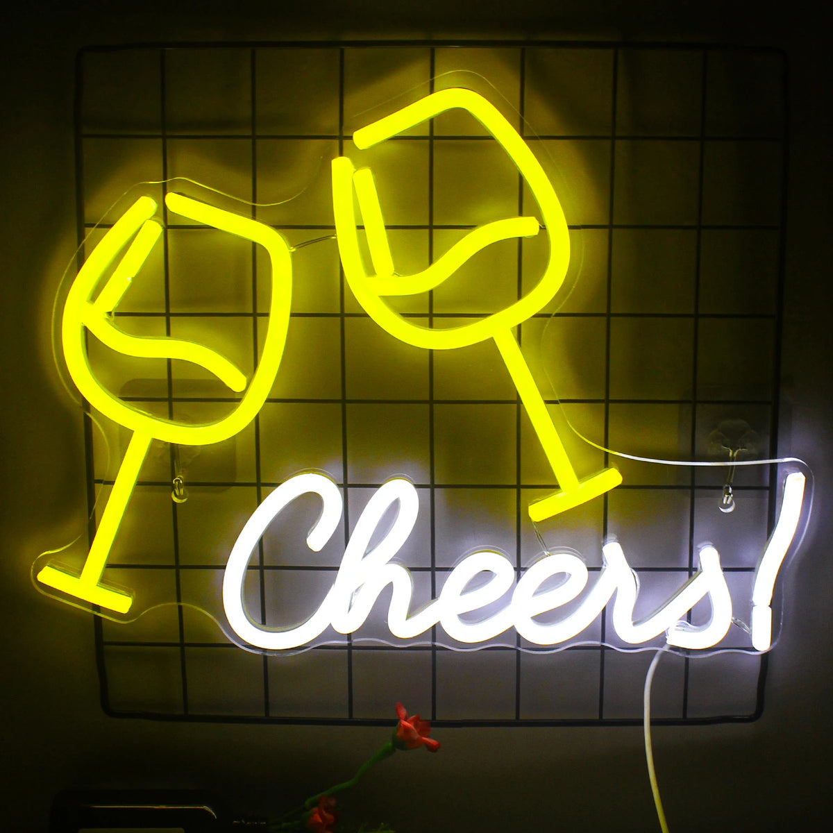 En levande LED-neonskylt med texten "Cheers" i ett lekfullt kursivt typsnitt är monterad mot en tegelvägg.