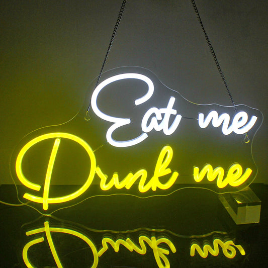 The image features a vibrant LED neon sign displaying the words "Eat Me Drink Me" in a whimsical, cursive font.