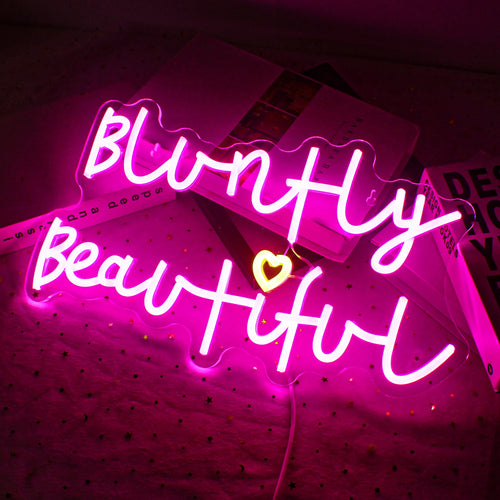 Bilden har en levande, handgjord LED-neonskylt som visar frasen "Bluntly Beautiful.