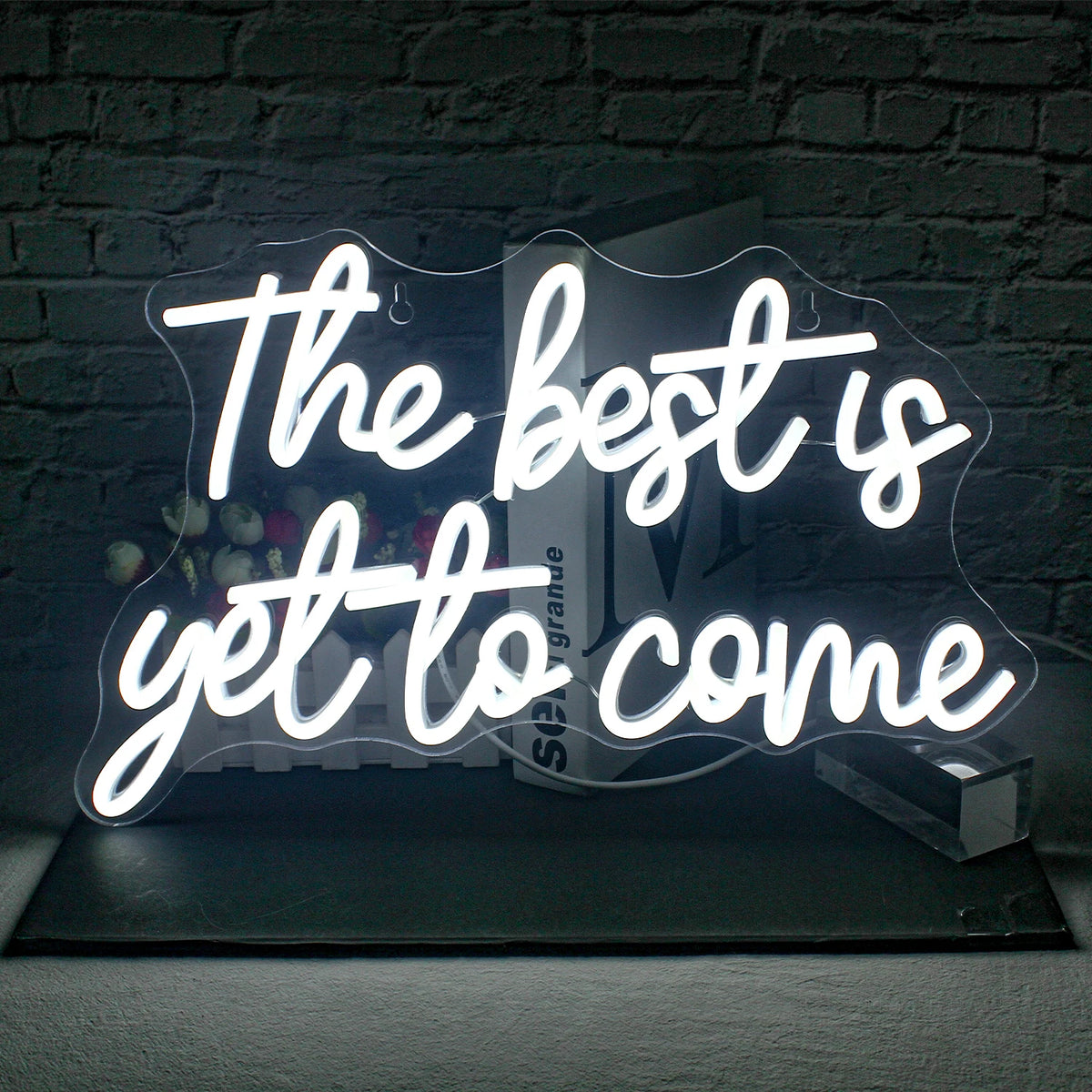 Bilden visar en levande, handgjord LED-neonskylt som läser "The Best is Yet to Come" i ett elegant, kursivt teckensnitt.