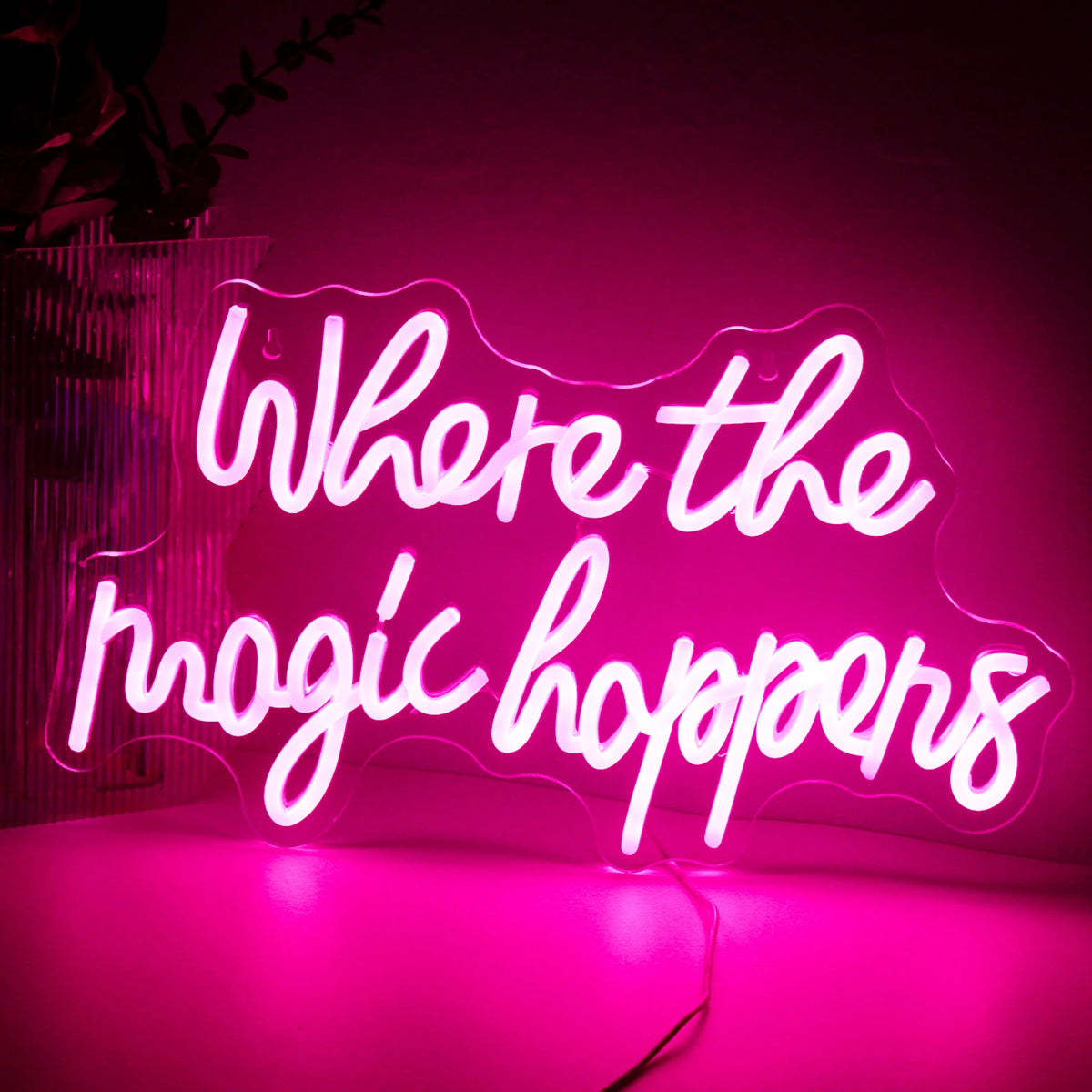 Bilden har en levande LED-neonskylt som läser "Where The Magic Happens" i ett elegant, lekfullt manustypsnitt.