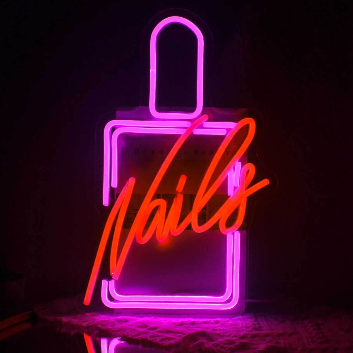Bilden har en levande LED-neonskylt som stavar ut ordet "Nails" i ett stilfullt kursivt teckensnitt.
