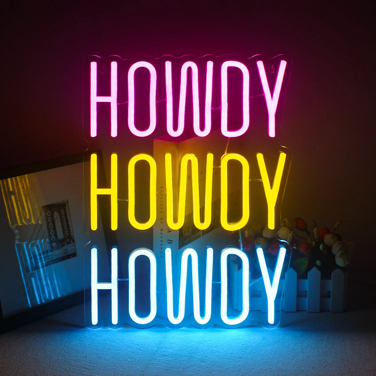 En levande, handgjord LED-neonskylt som visar ordet "Howdy" i ett lekfullt, kursivt teckensnitt.