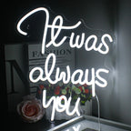 The image features a handcrafted LED neon sign displaying the words "It Was Always You" in elegant, cursive script.