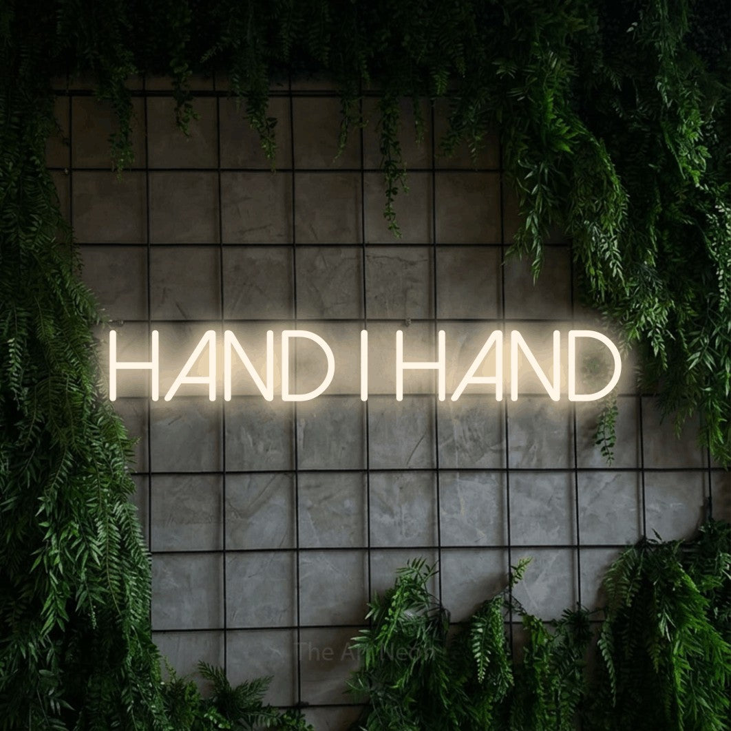 LED neon sign reading “hand i hand”, arranged in a single line.
