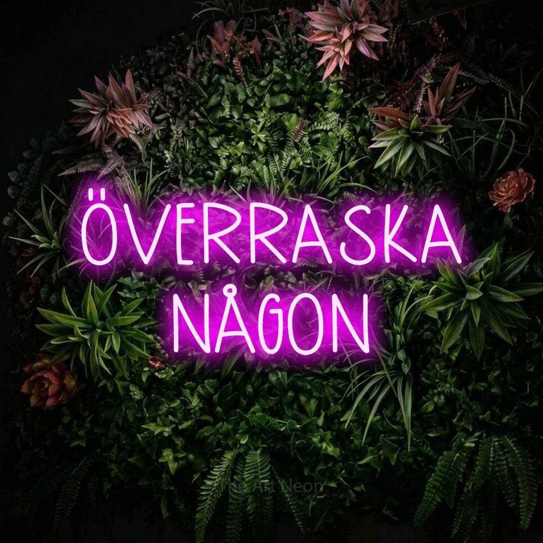 LED neon sign reading “ÖVERRASKA NÅGON”, arranged in 2 lines.