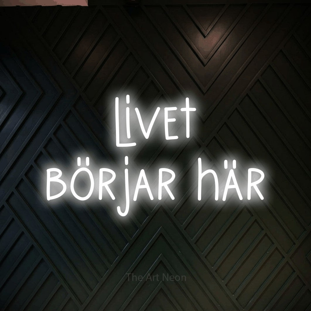 LED neon sign reading “livet börjar här”, arranged in 2 lines.